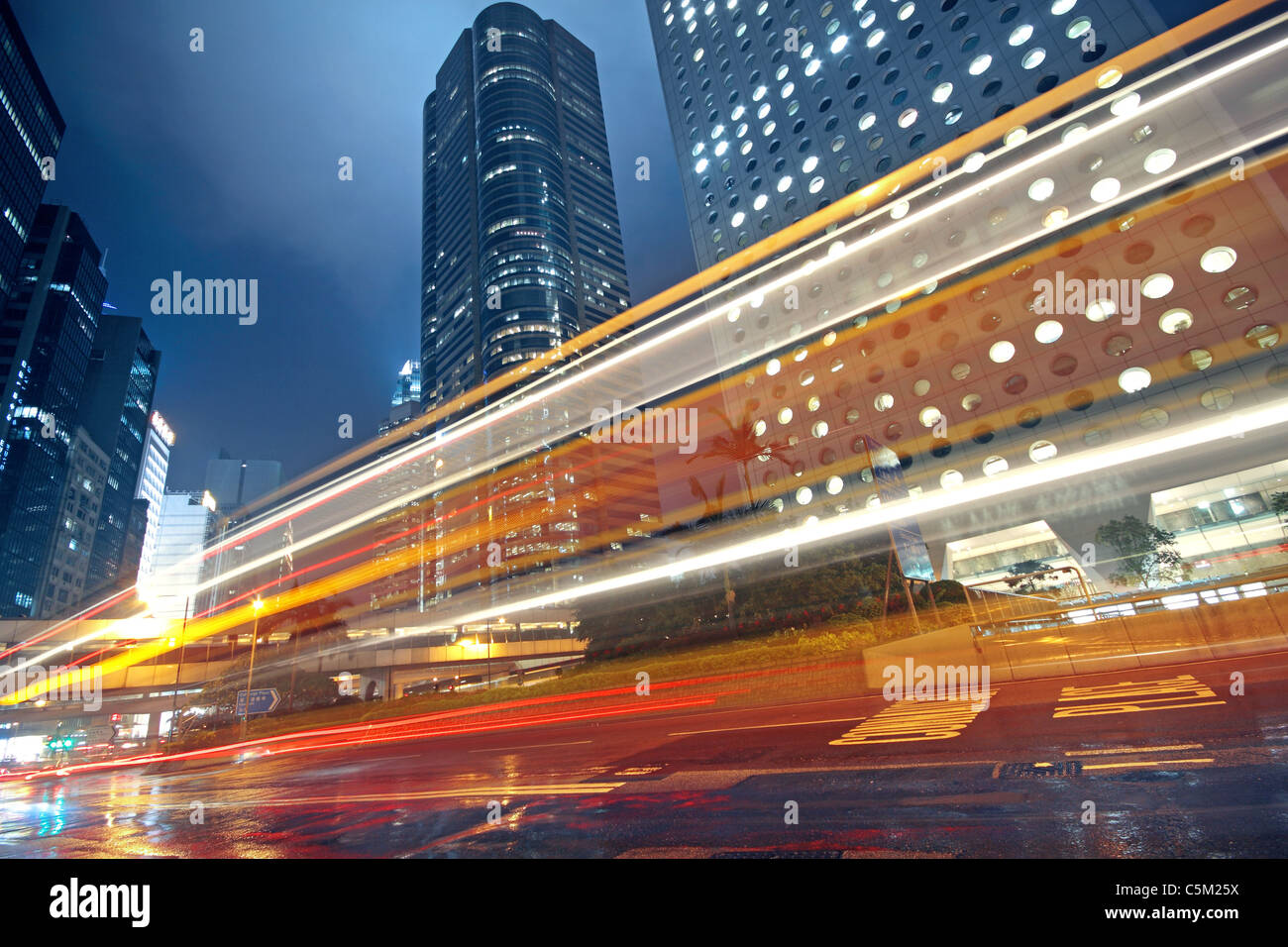 traffic light trails in the street by modern building Stock Photo