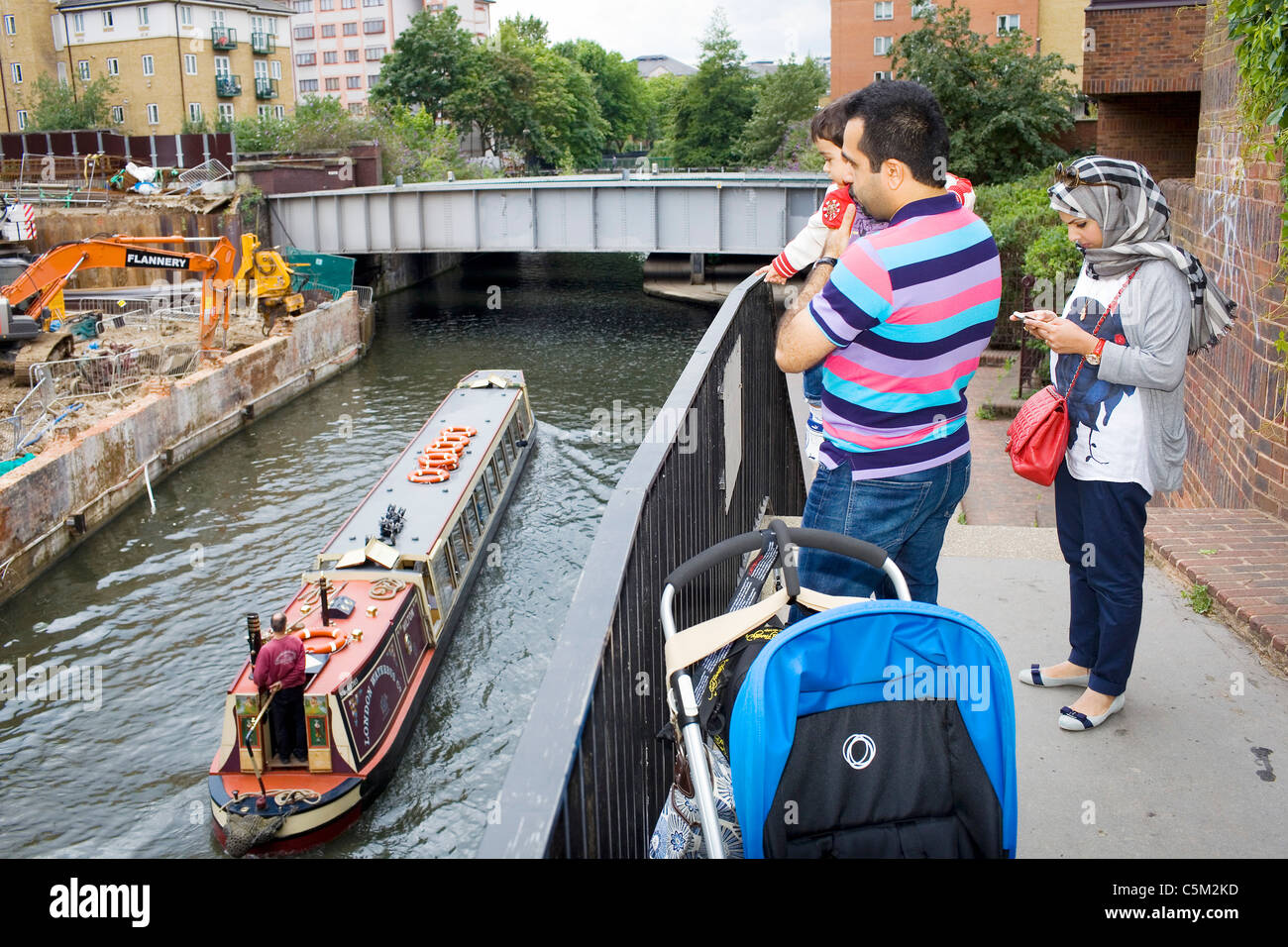 An family watch a boat pass on a London canal. Stock Photo