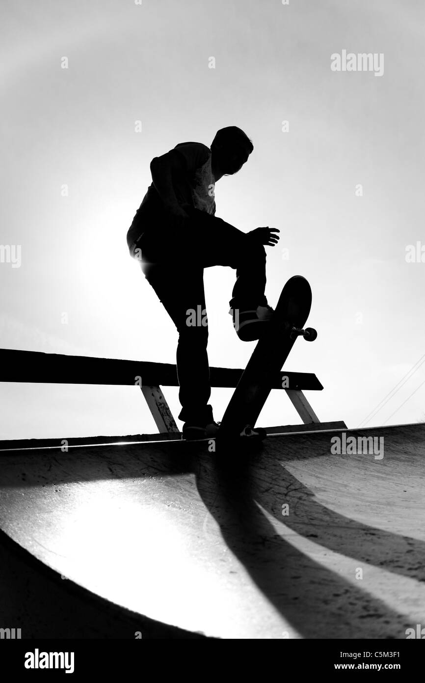 Silhouette of a young skateboarder at the top of the ramp. Stock Photo