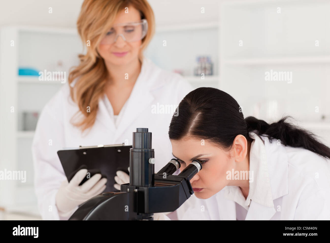 Dark-haired scientist and her assistant conducting an experiment Stock Photo