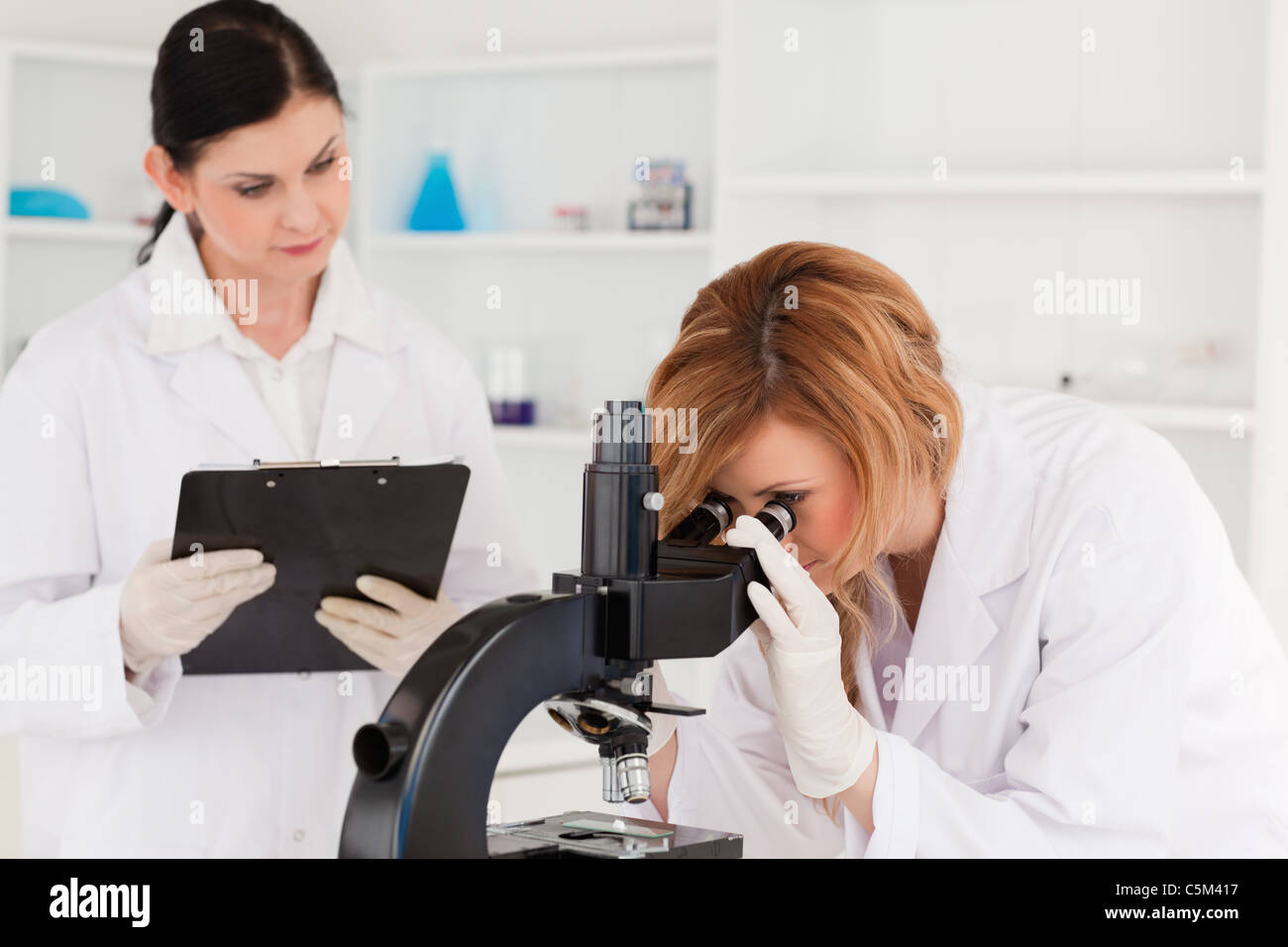 Blond scientist and her assistant conducting an experiment Stock Photo