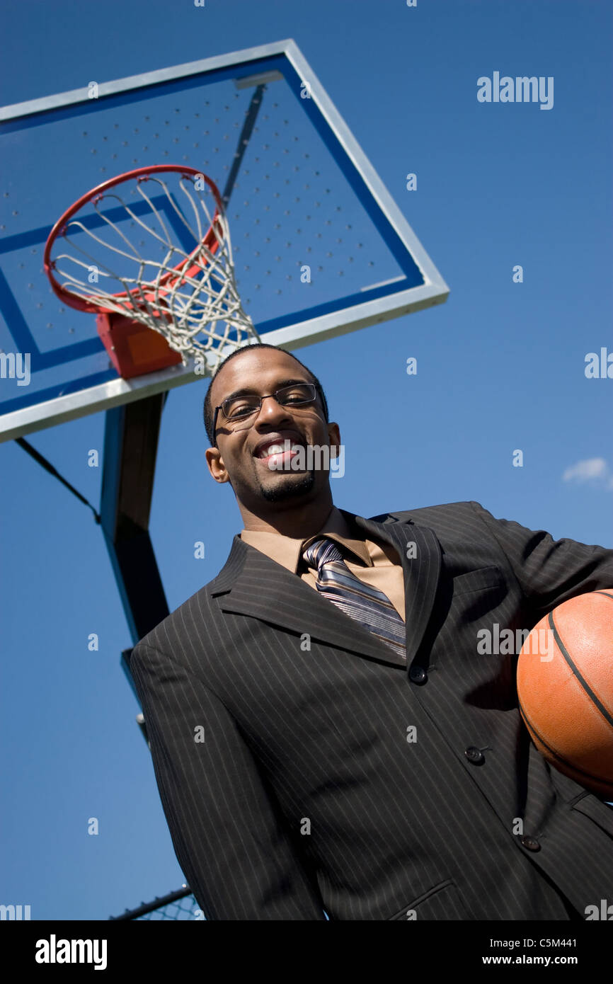 African American man in a business suit posing with a basketball. He