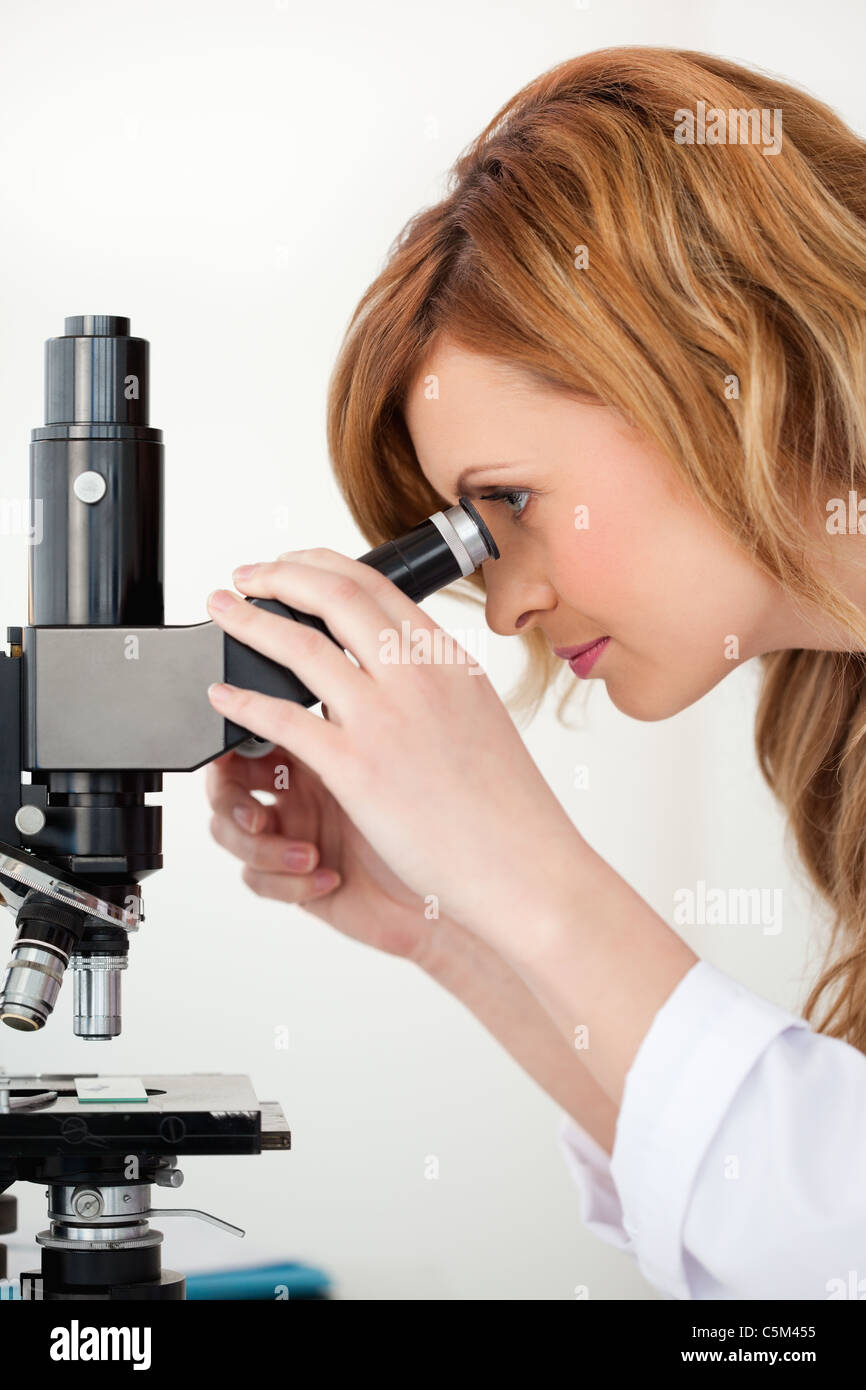 Cute blond-haired scientist looking through a microscope Stock Photo