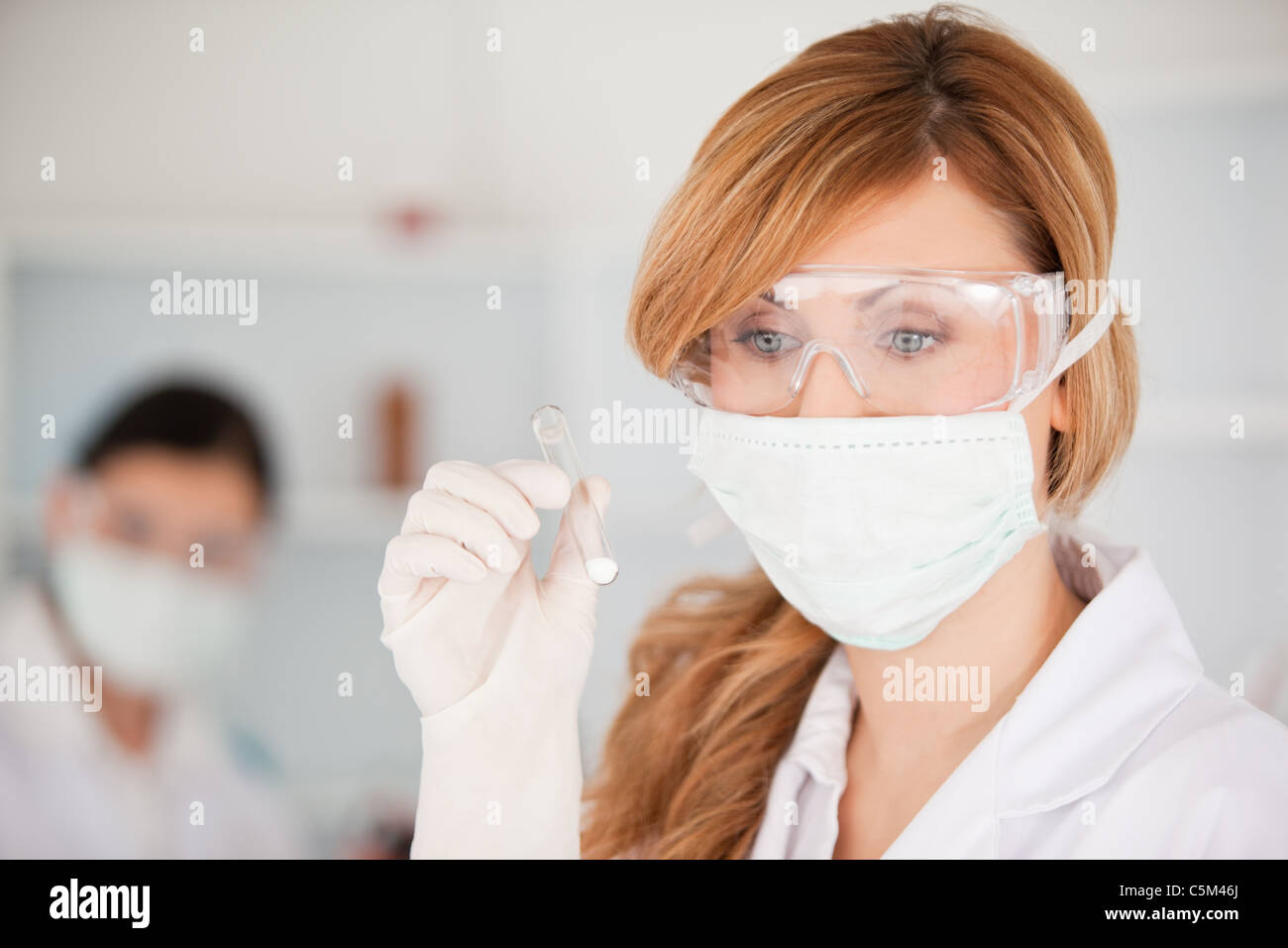 Blond scientist with mask holding a test tube Stock Photo