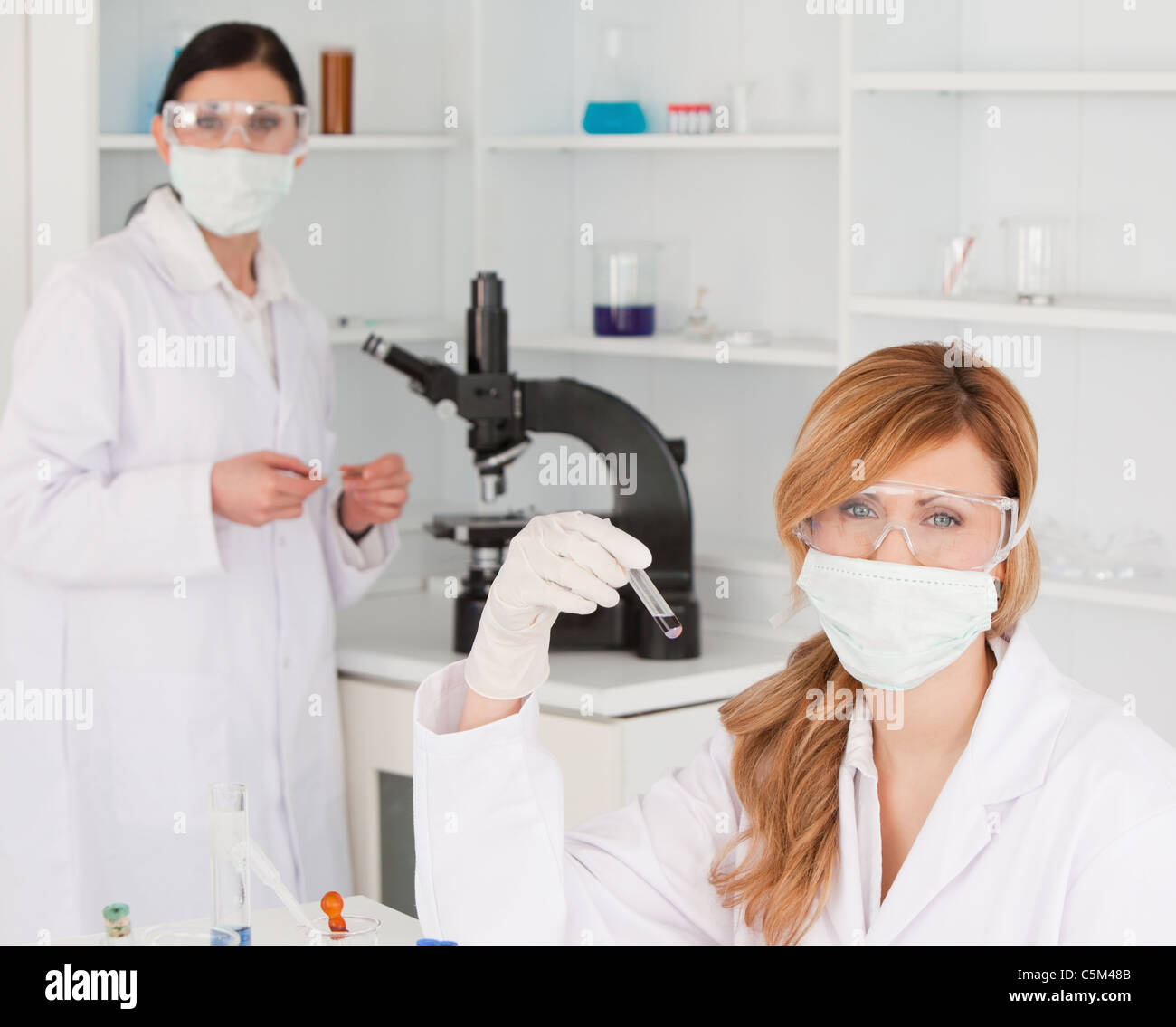 Blonde and dark-haired scientists posing in lab Stock Photo