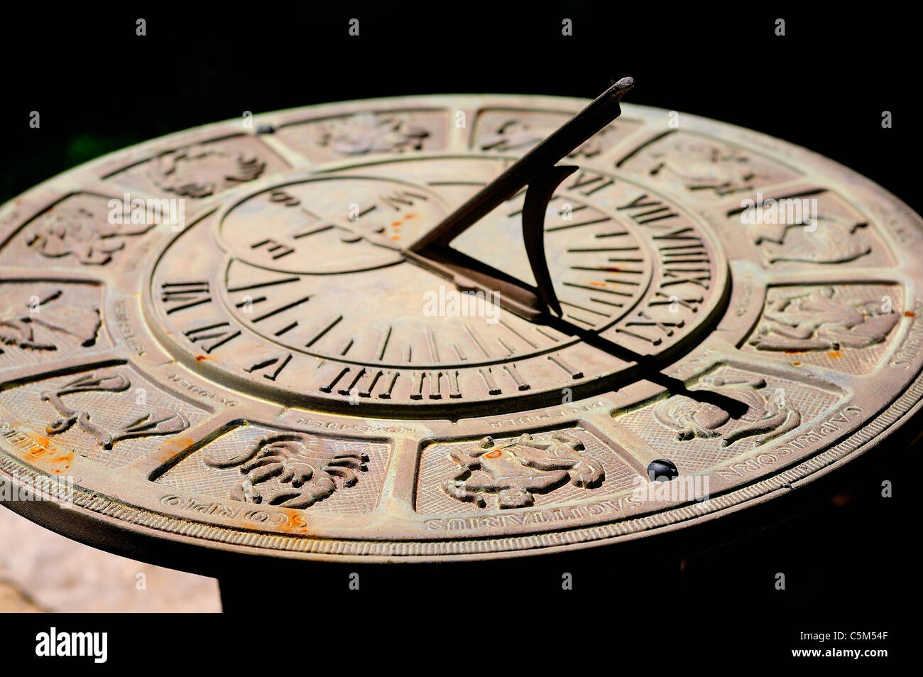 Sundial with Zodiac signs and figures surrounding Roman numeral times. Stock Photo