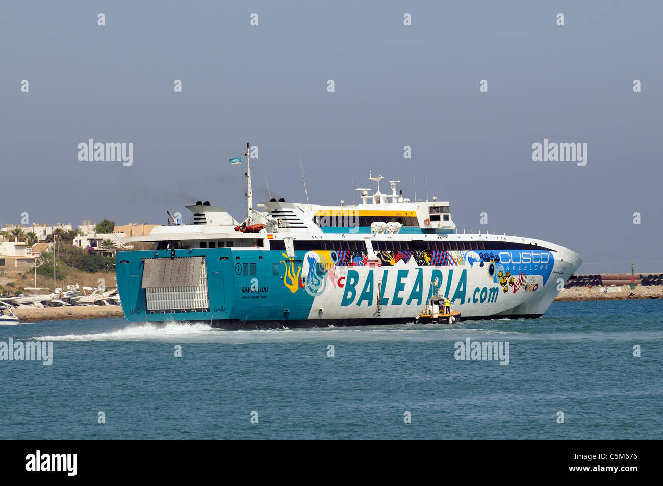 Super Fast Ferry the Ramon Llull departing Eivissa Port on the Spanish Island of Ibiza with pilot boat in attendance Stock Photo