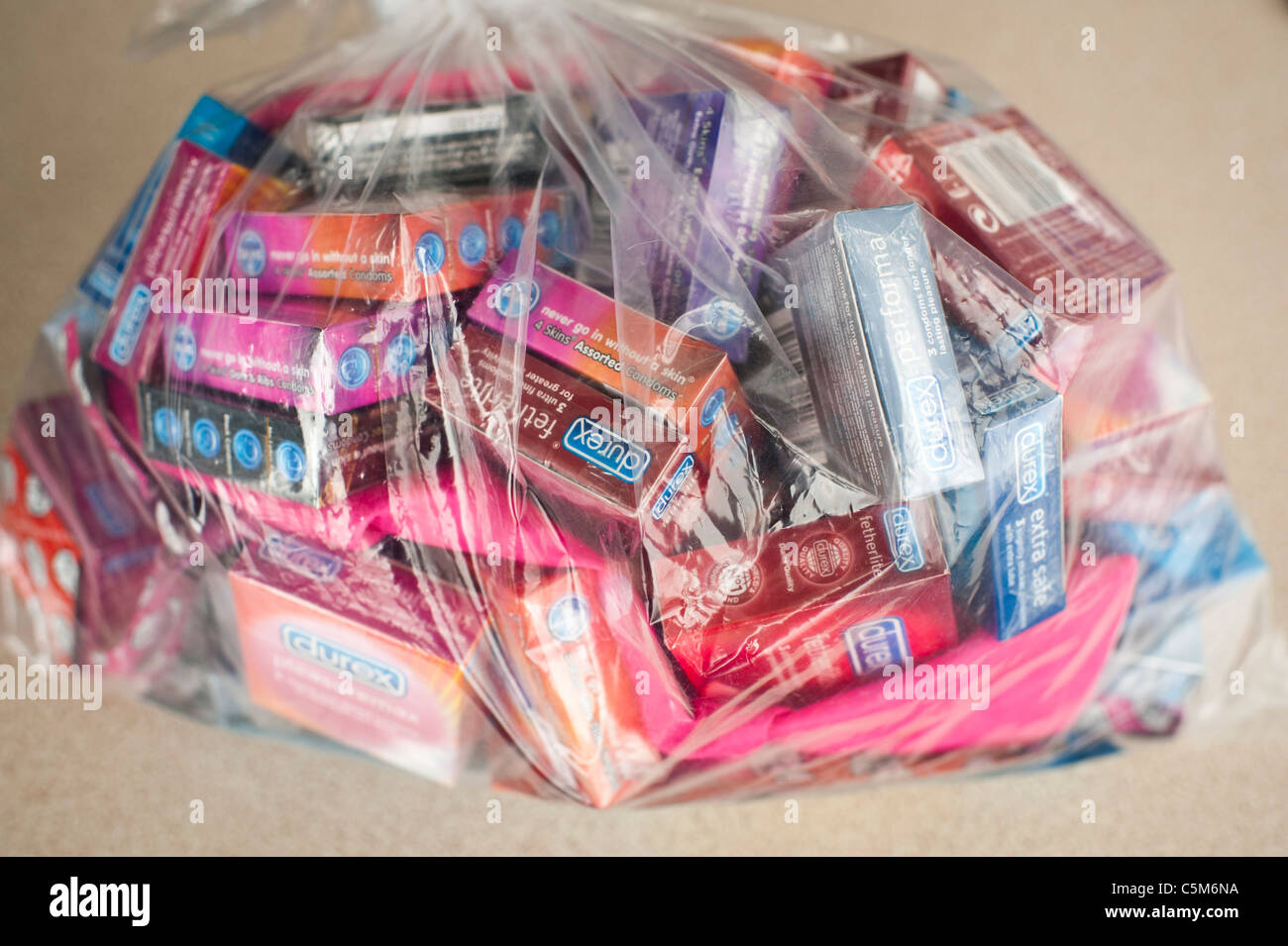 a plastic bag full of packs of various types of condoms, uk Stock Photo