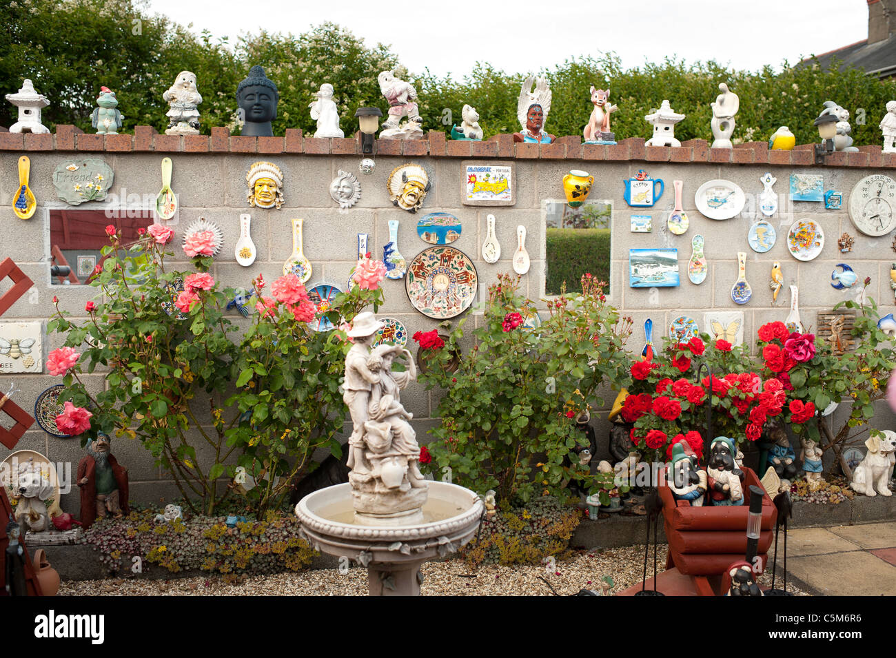 A patio garden or back yard full of plastic gnomes and other statues, Wales UK Stock Photo