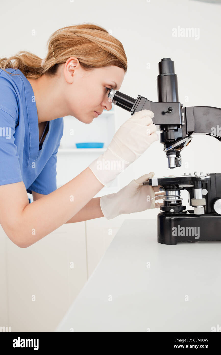 Blond-haired scientist looking through a microscope Stock Photo