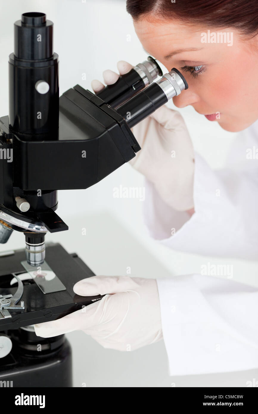 Pretty red-haired scientist looking through a microscope Stock Photo