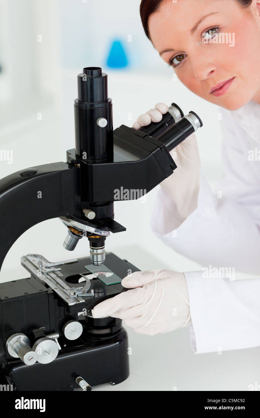 Cute red-haired scientist looking through a microscope Stock Photo