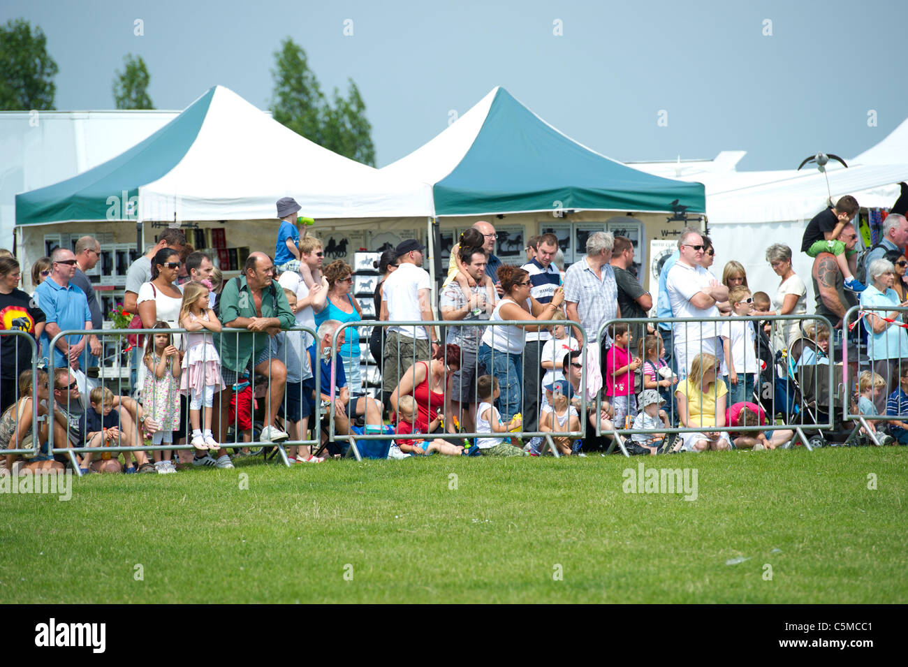 Image of mixed crowd at side of arena of a county show on summers day. Stock Photo