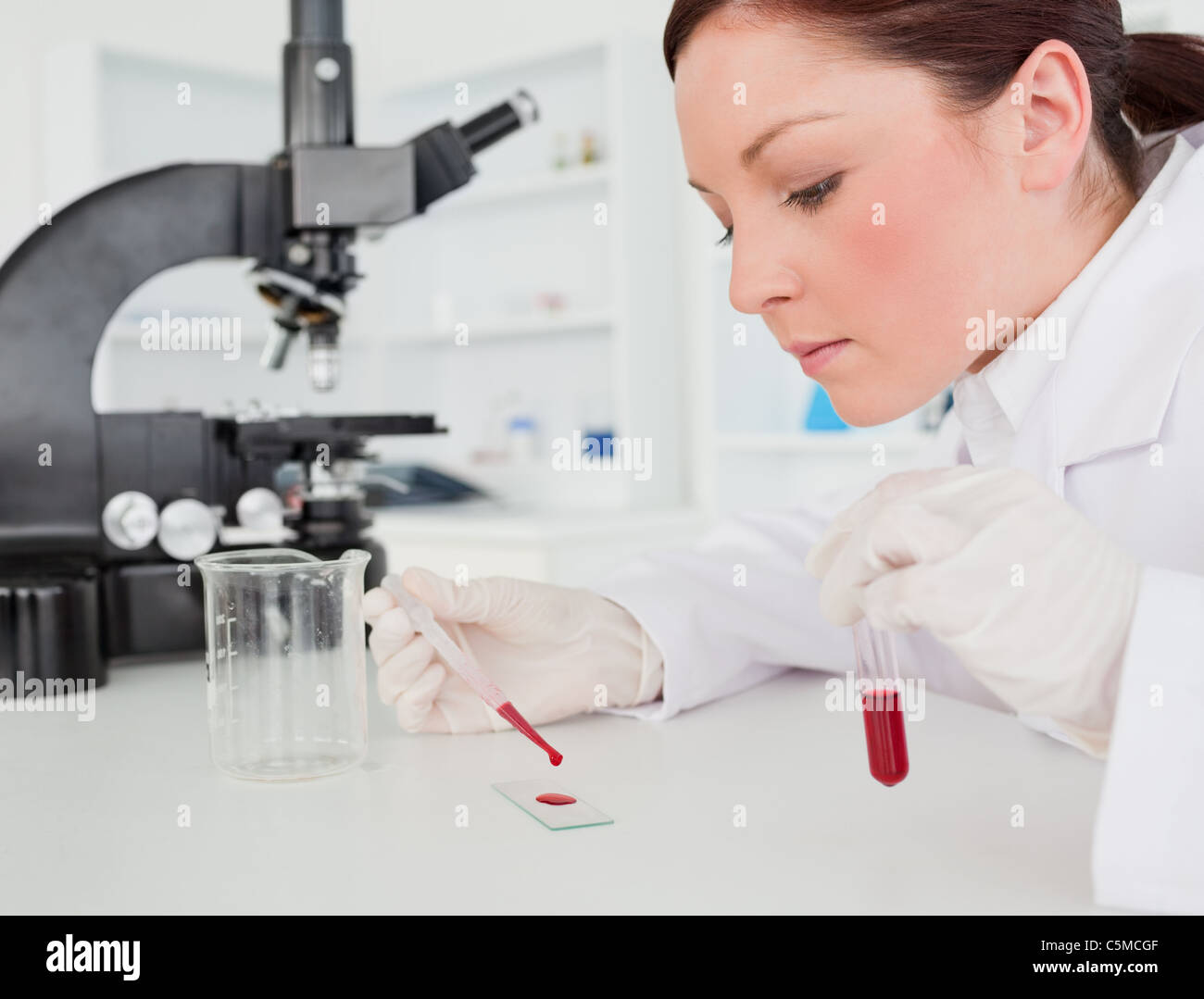 Cute red-haired female scientist doing an experiment in a lab Stock Photo