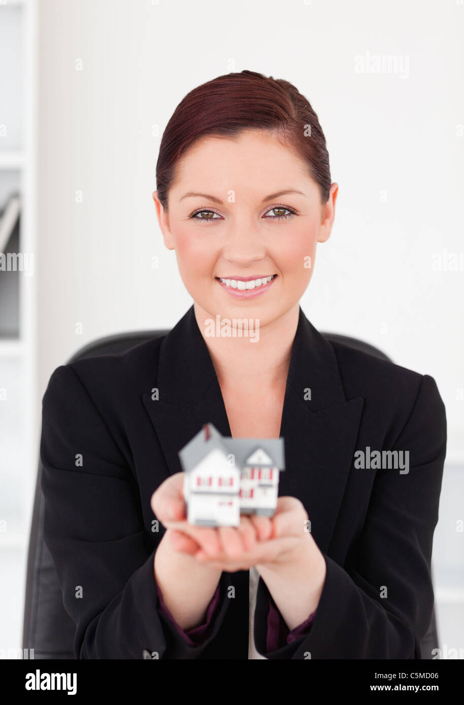 Cute red-haired woman in suit holding a miniature house Stock Photo - Alamy