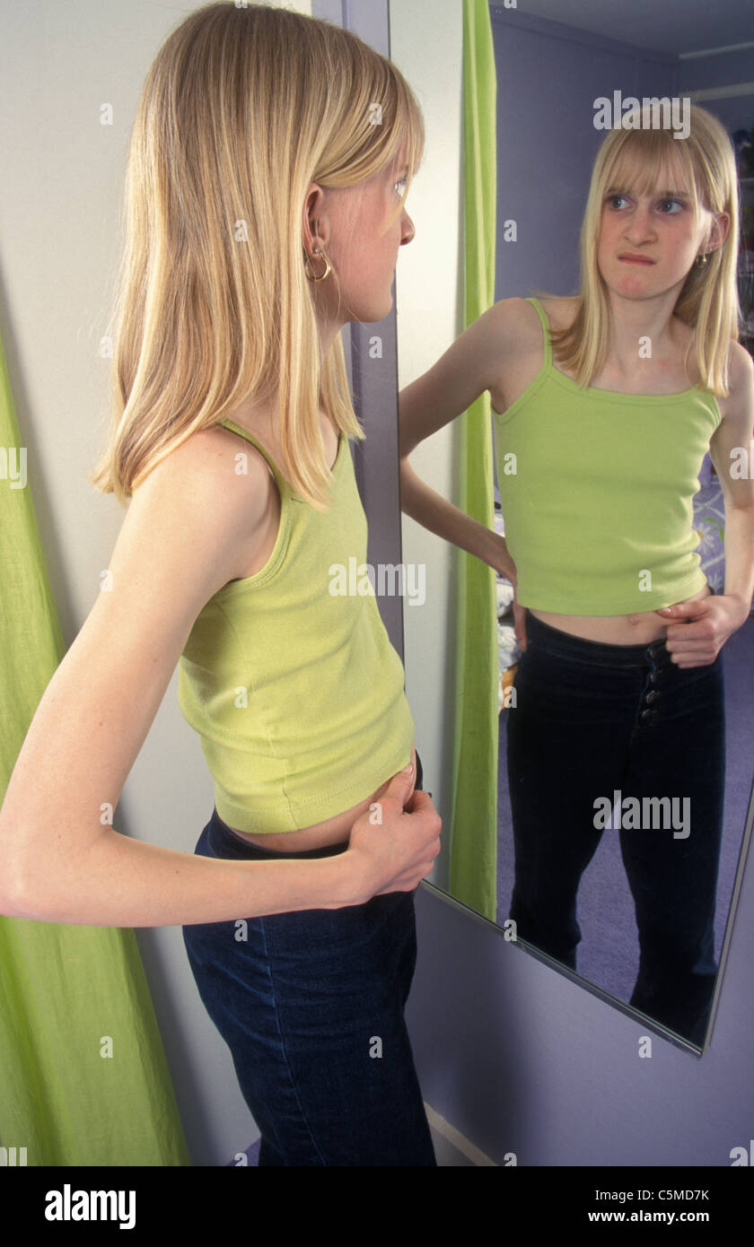 thin girl looking in mirror Stock Photo