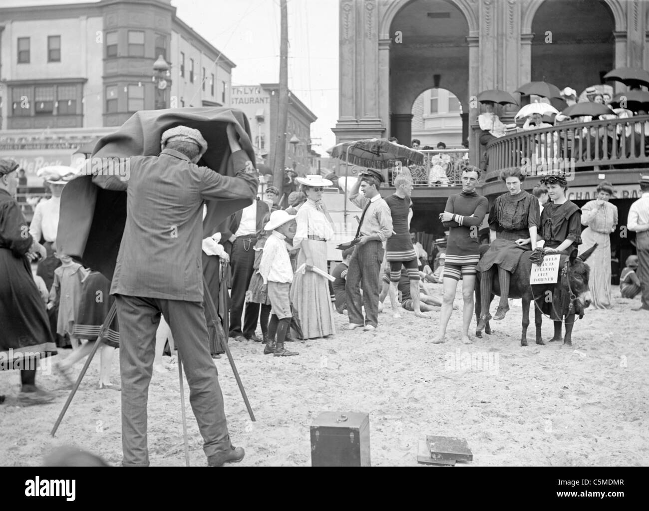 Man and women posed on donkey for photo at crowded beach, Atlantic City, NJ, USA circa 1915 Stock Photo