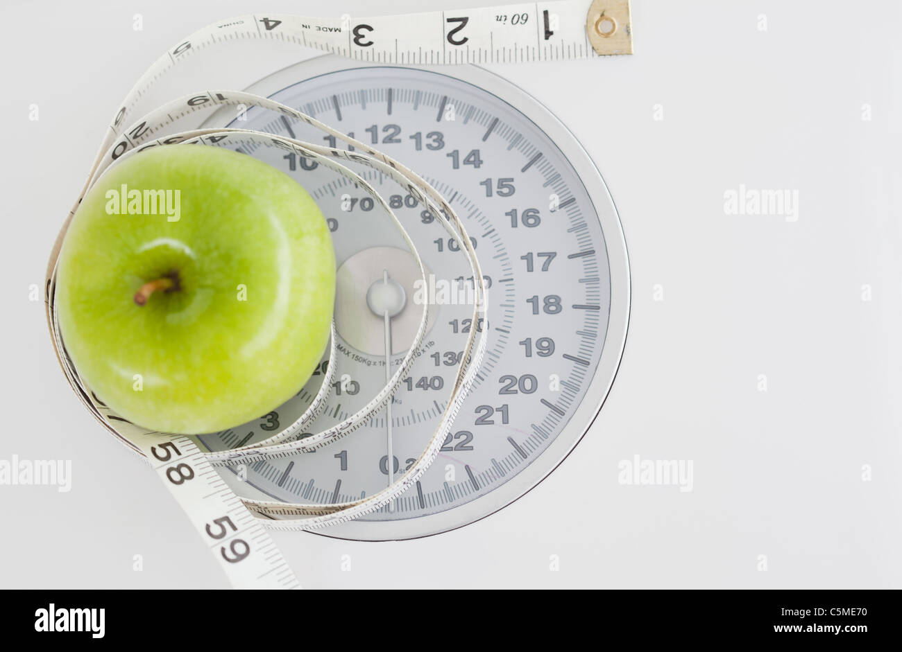 Green apple circled with a tape measure and weigh-scale Stock Photo - Alamy
