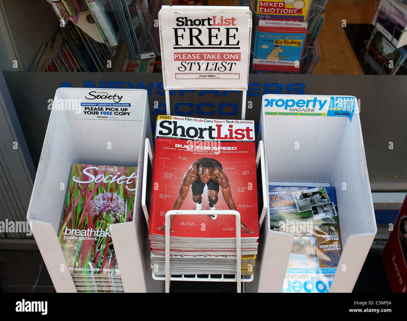 Stacks of free sheets and magazines in display bins outside a shop in Brighton, East Sussex, UK. Stock Photo
