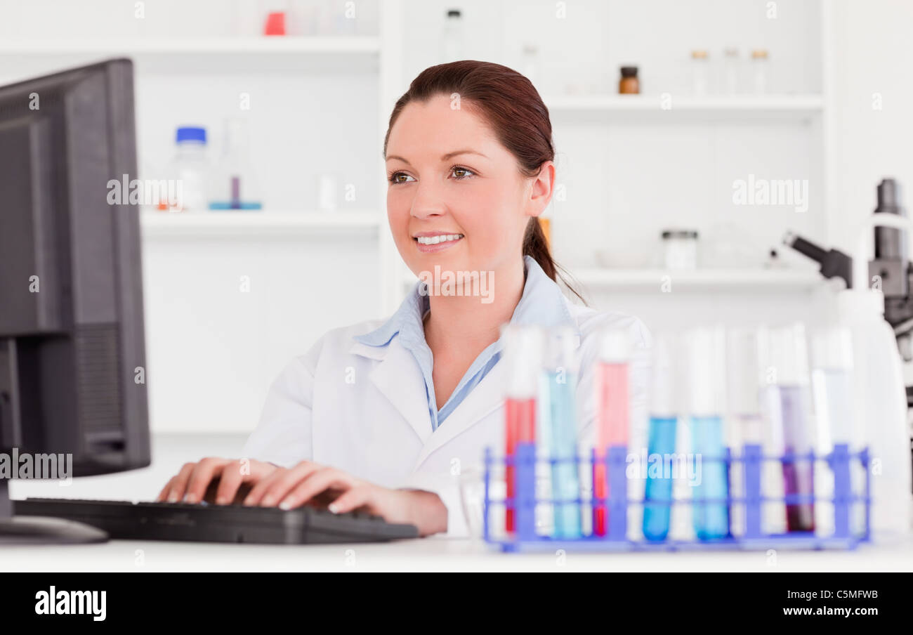 Red-haired scientist typing a report with her computer Stock Photo