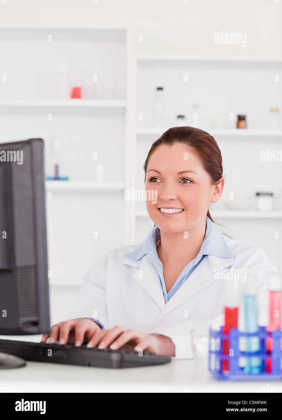 Smiling scientist typing a report with her computer Stock Photo