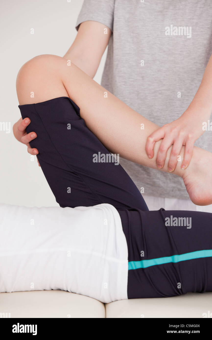Portrait of a masseuse stretching the leg of a youn woman Stock Photo