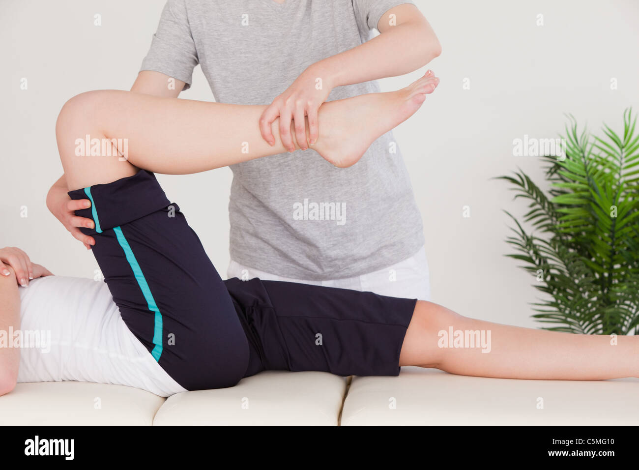 Masseuse stretching the right leg of a young woman Stock Photo
