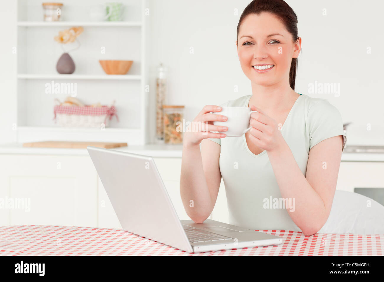 Attractive woman relaxing on her laptop while drinking a cup of tea Stock Photo