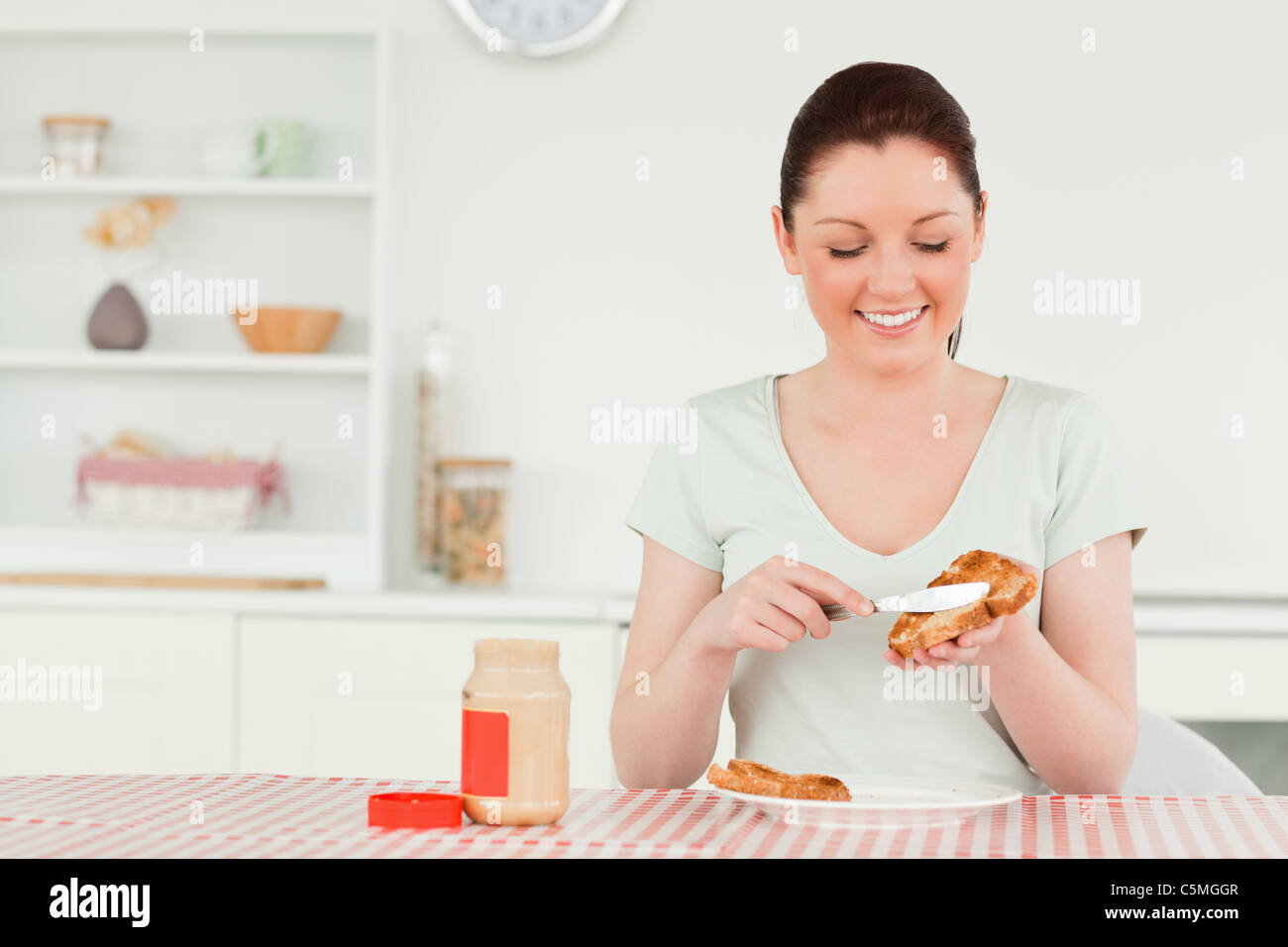 Good looking woman preparing a slice of bread and marmalade Stock Photo