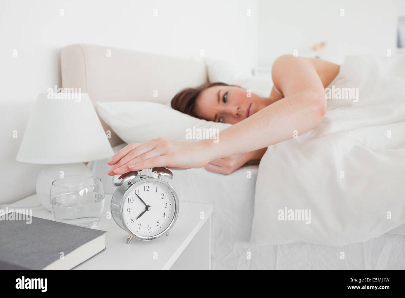 Gorgeous brunette woman awaking with a clock while lying Stock Photo ...