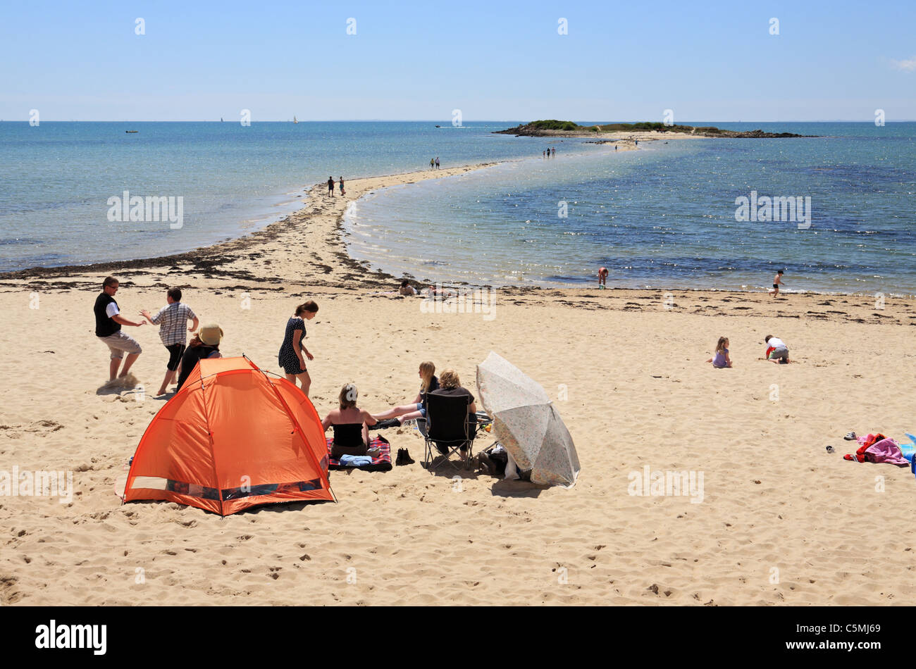 Families playing on Le M'En Du beach with the Ile De Stuhan in the background, near Carnac, Brittany, France Stock Photo