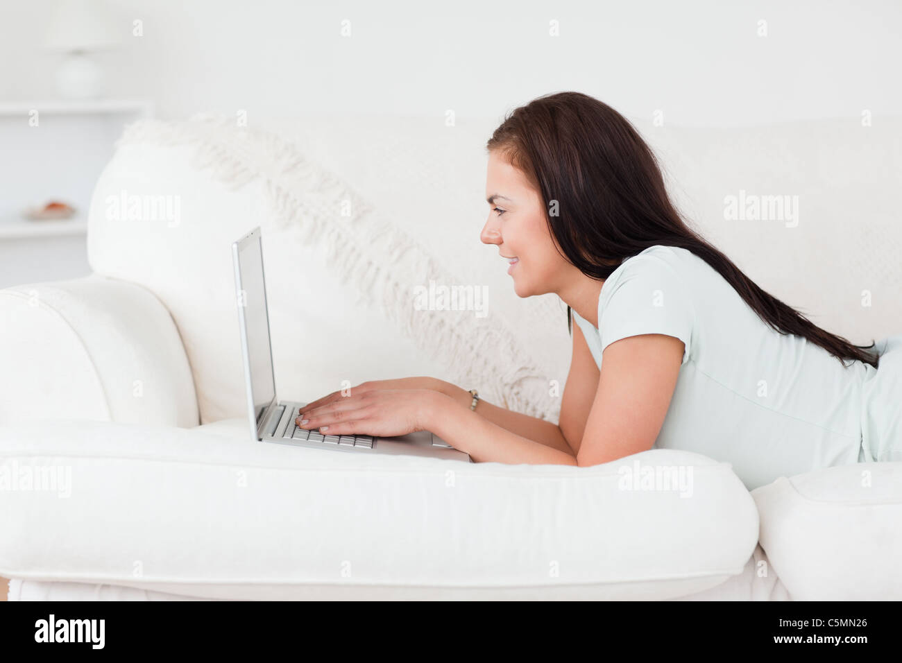 Cute woman on a sofa using a laptop Stock Photo - Alamy