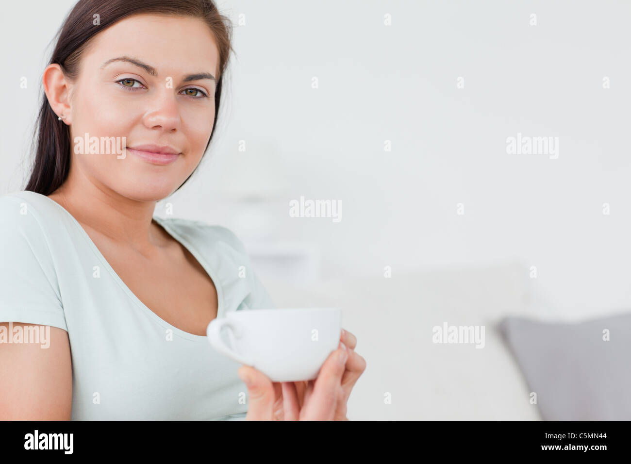 Close up of a charming woman sitting on a sofa with a cup of tea Stock ...
