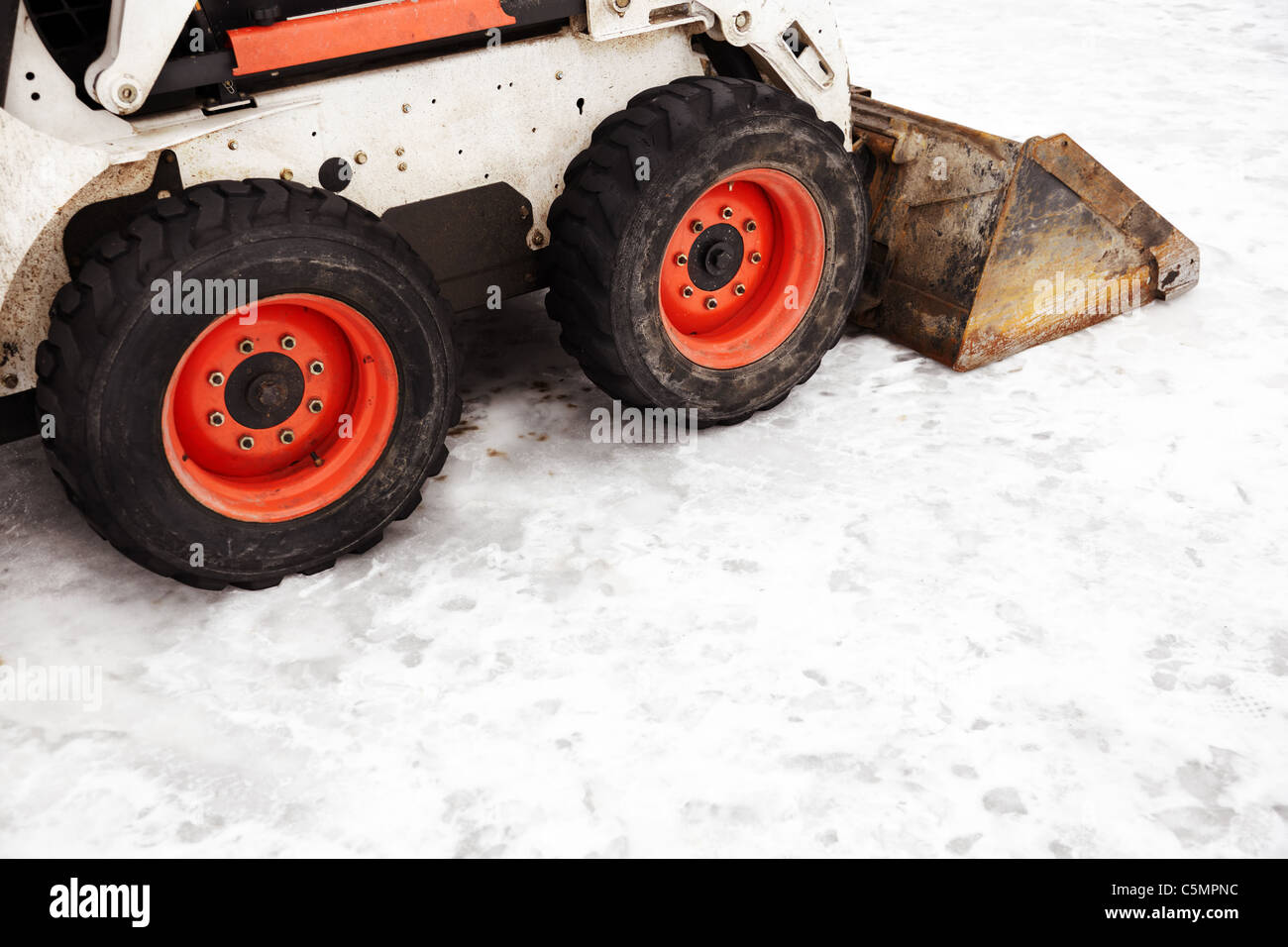 mini loader with snowplow on the winter street, selective focus on center Stock Photo