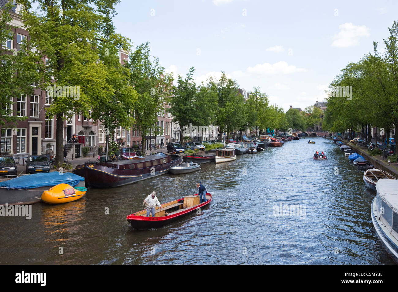 Small barge sailing on a city canal, Amsterdam, Netherlands Stock Photo