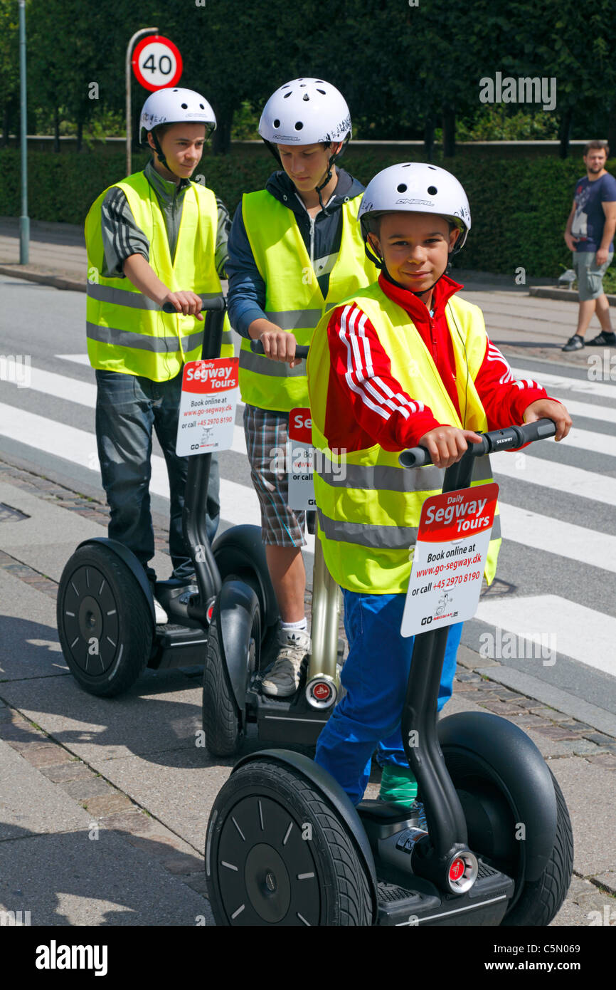 Young tourists in yellow safety vests and helmets with radio receiver on a Segway sightseeing in the city of Copenhagen, Denmark Stock Photo