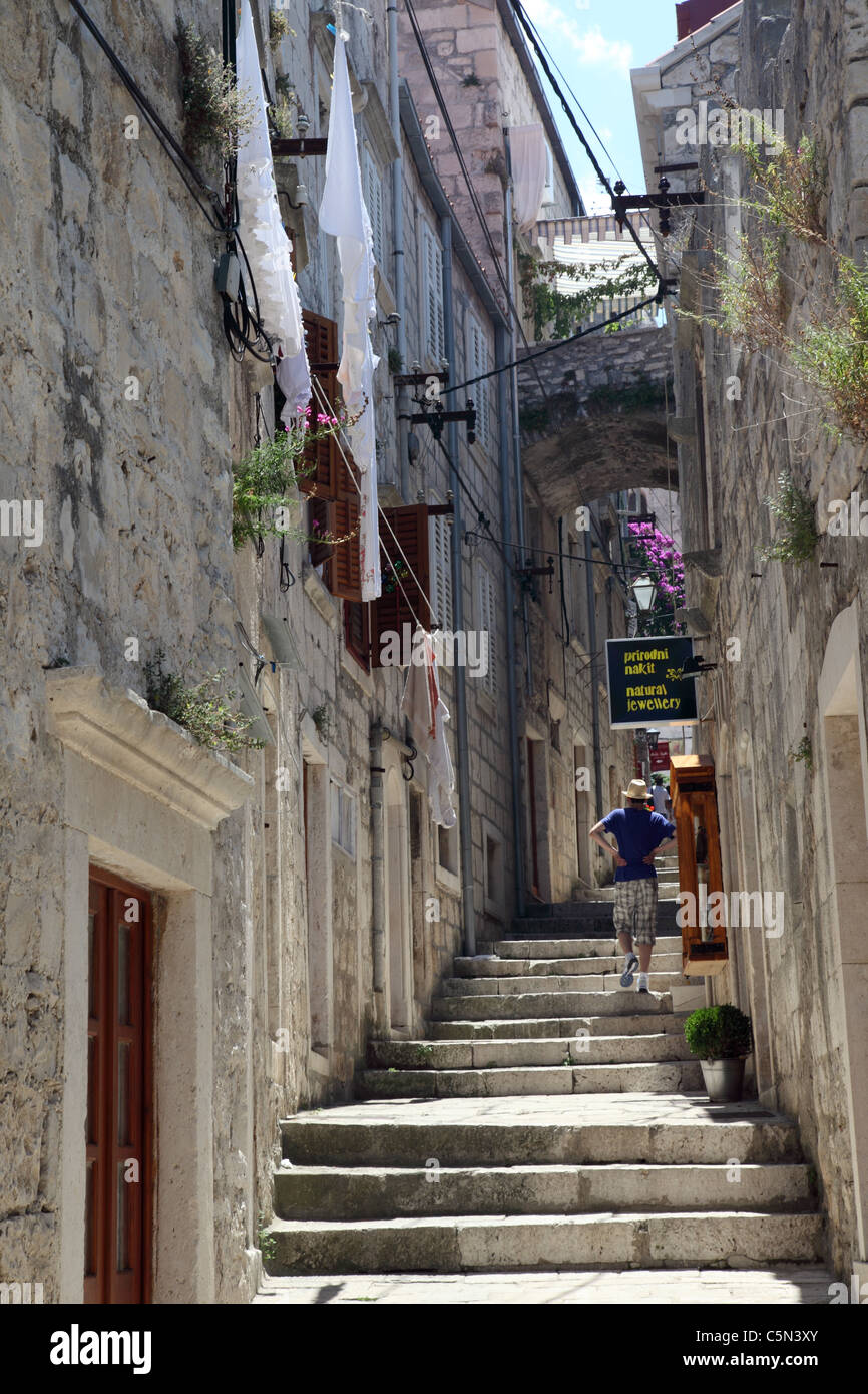 A tourist walking up a stepped narrow alley in Korcula Island, Dalmatia, Croatia Stock Photo