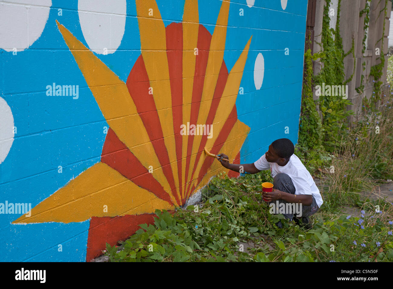 Detroit, Michigan - High school volunteers paint on an empty building. They are working through the Summer in the City program. Stock Photo