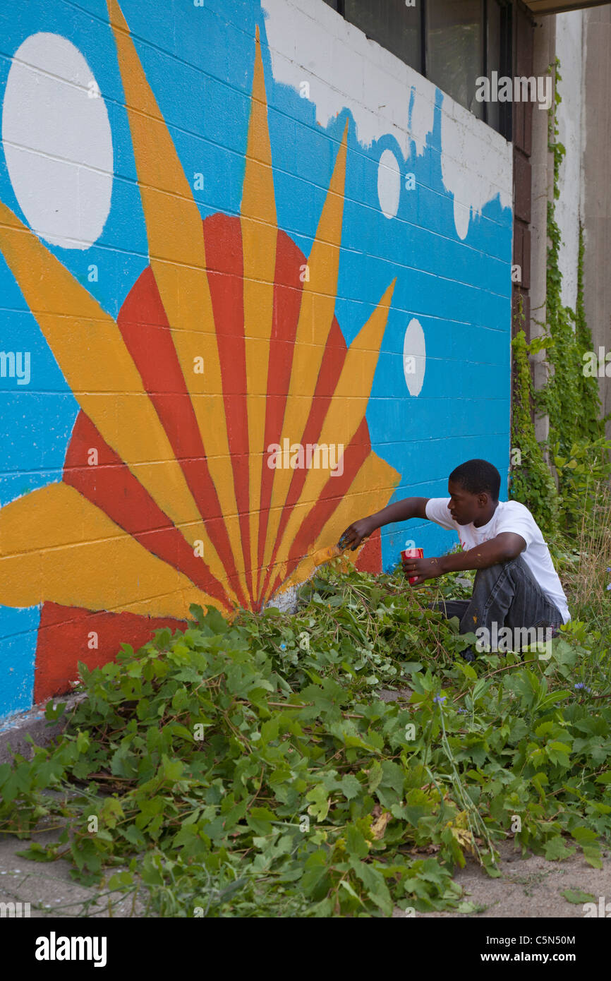 Detroit, Michigan - High school volunteers paint on an empty building. They are working through the Summer in the City program. Stock Photo