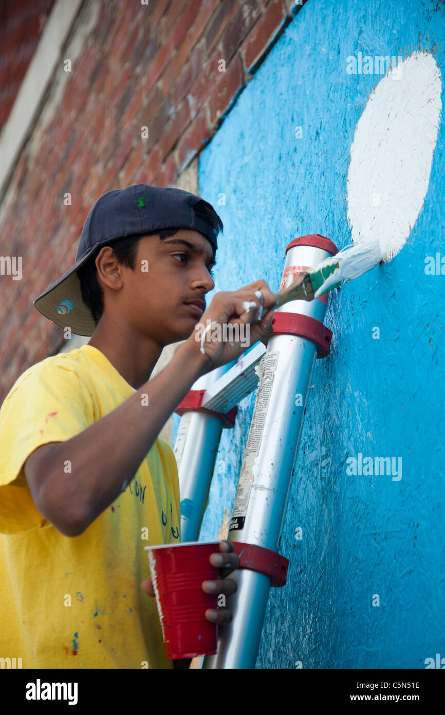 Detroit, Michigan - High school volunteers paint on an empty building. They are working through the Summer in the City program. Stock Photo