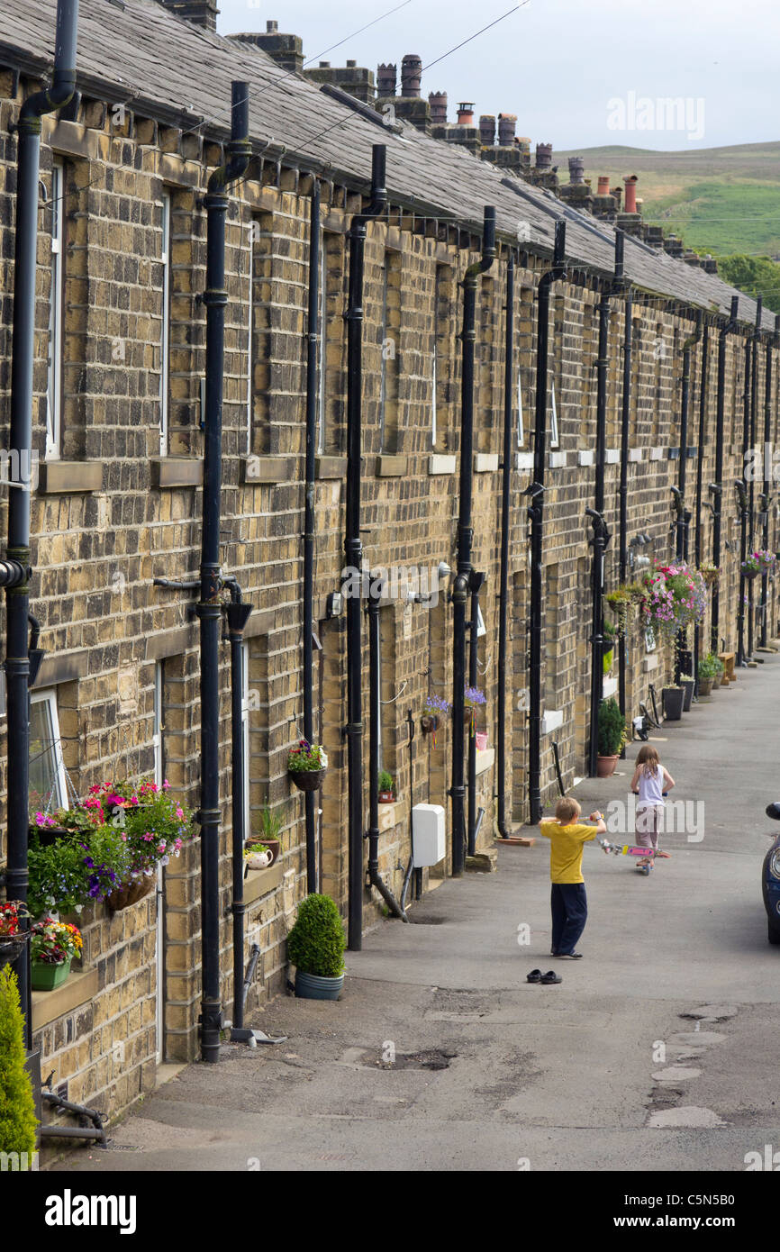 Children playing in a street of stone terraced houses in Marsden in the