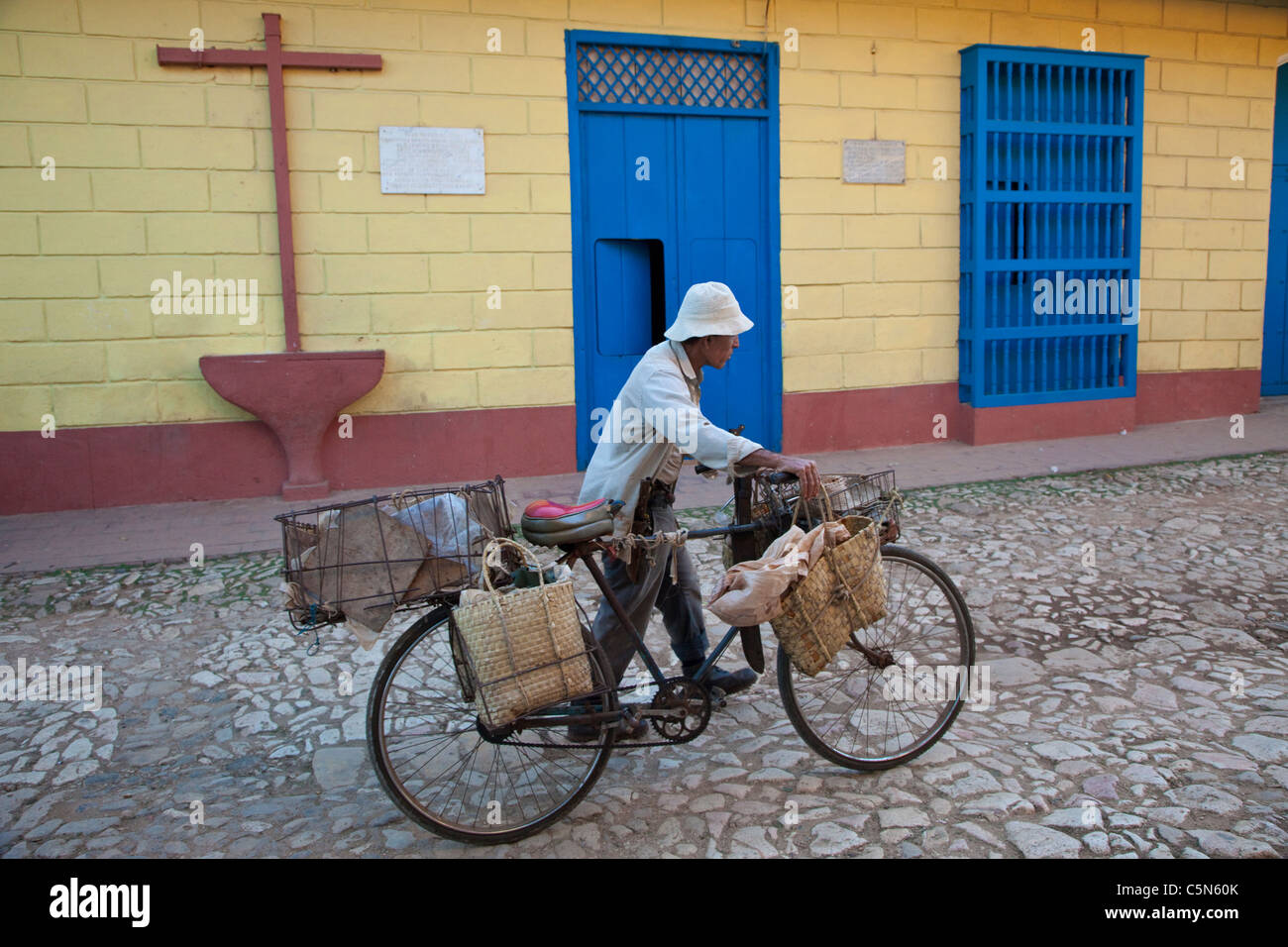Cuba, Trinidad. Man Pushing Bicycle past house where Alexander Humboldt, for whom the Humboldt current is named, stayed in 1801. Stock Photo