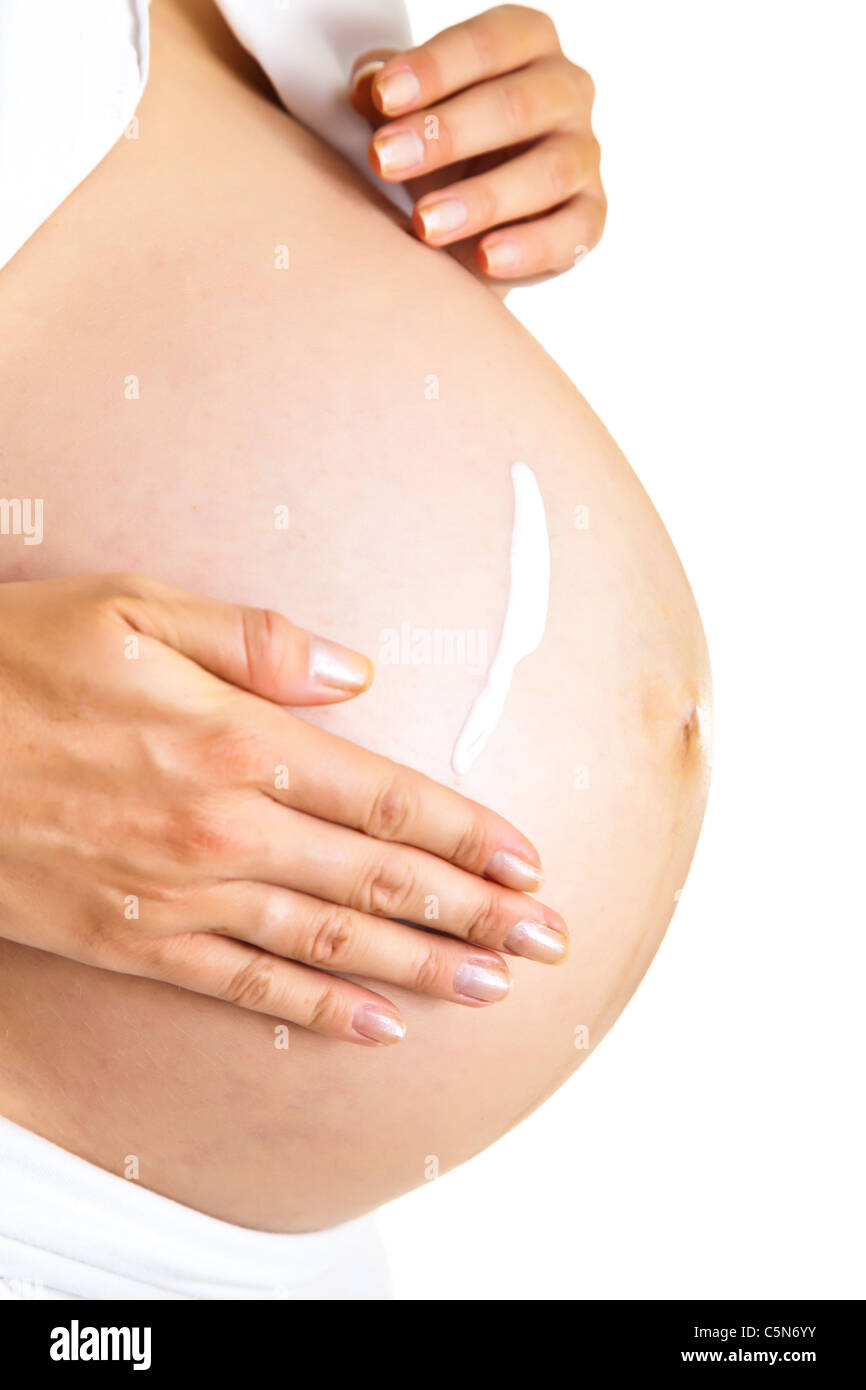 Pregnant woman moisturising belly to avoid stretch marks isolated on white Stock Photo