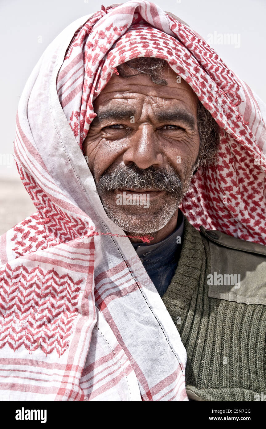 A portrait of a Bedouin Arab shepherd man of the Rowala tribe wearing a red checkered headscarf, in the Badia region of the Eastern Desert of Jordan. Stock Photo