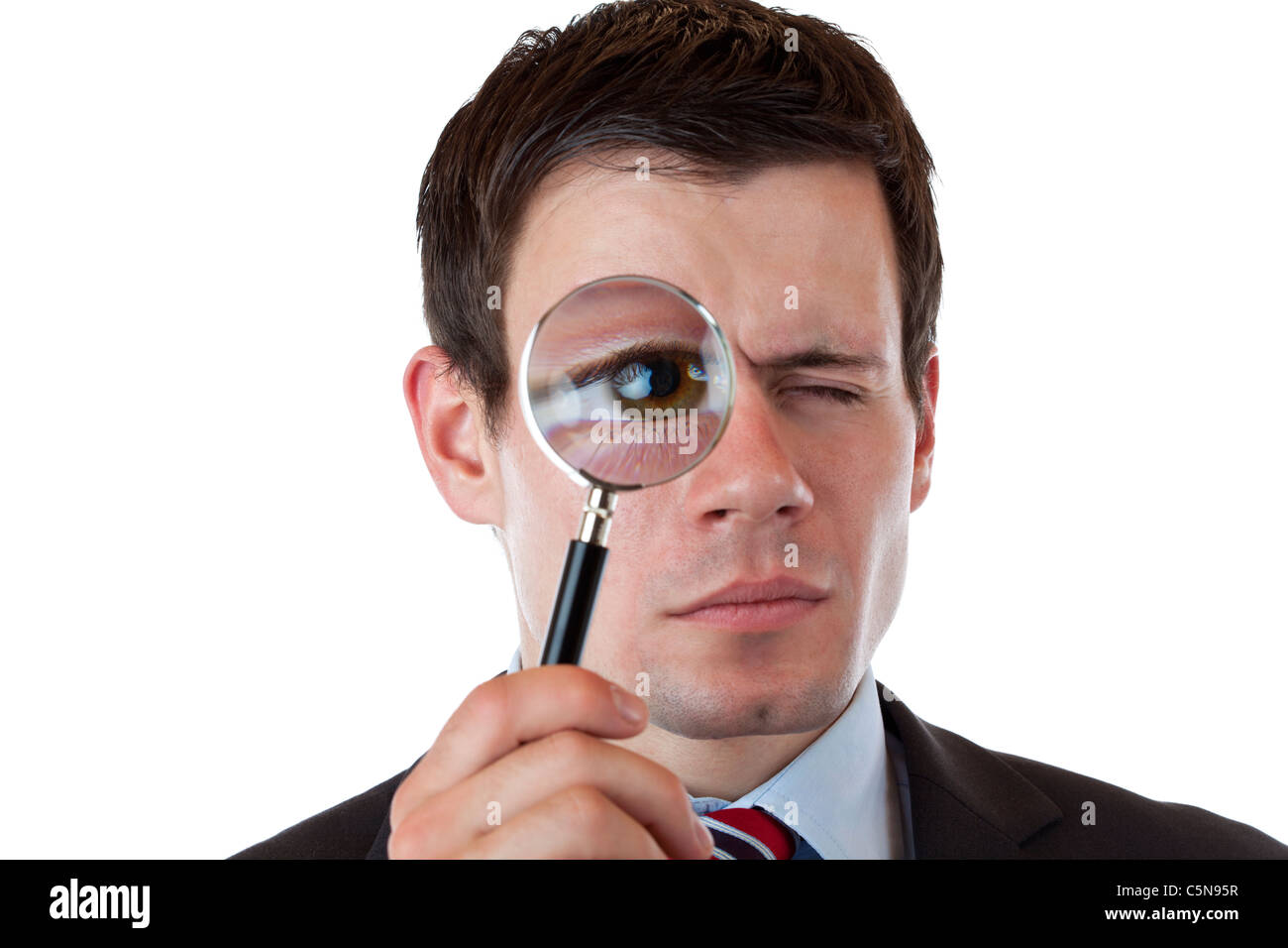 Businessman with magnifying glass in front of his eye. Isolated on white background. Stock Photo