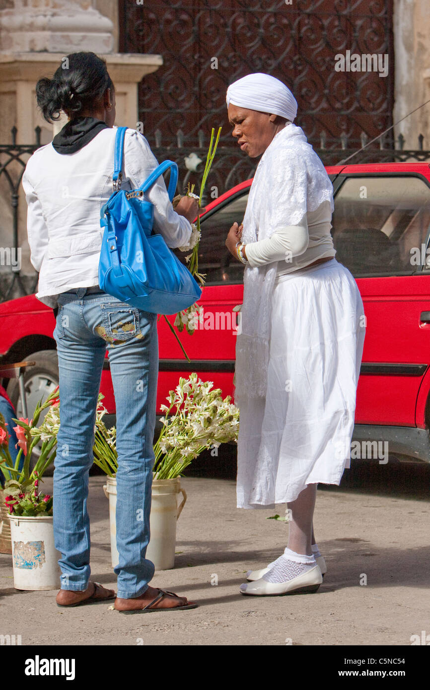 Cuba, Havana. Woman Practitioner of Santeria Buying Flowers before entering Church of La Merced. Stock Photo