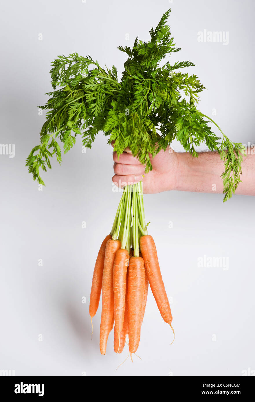 A man holding a bunch of carrots Stock Photo