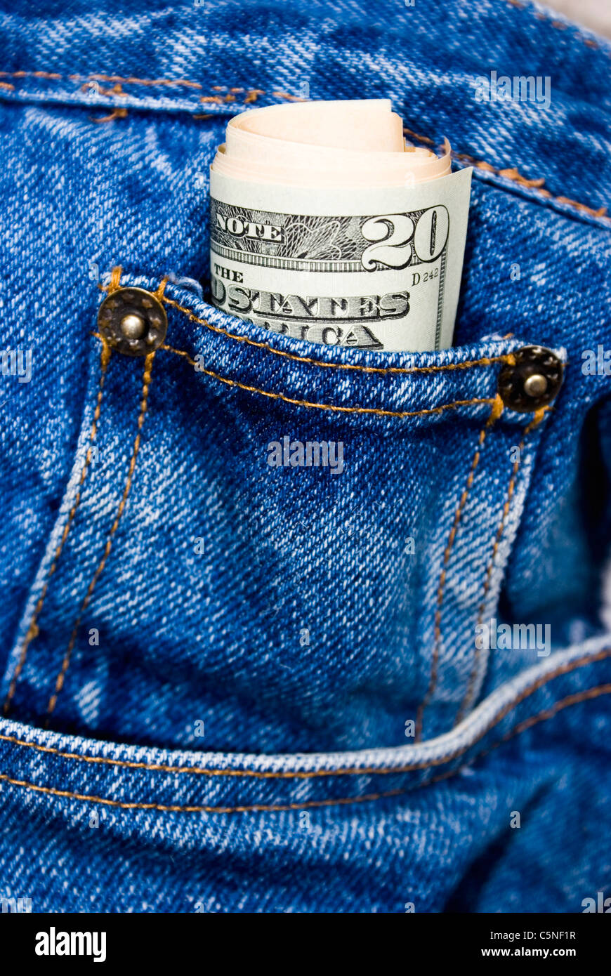 A roll of 20 dollar bills in pocket of blue jeans Stock Photo