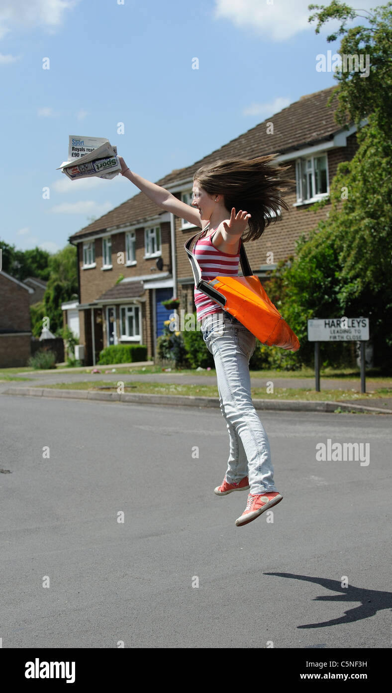Young girl happy with her spare time job delivering newspapers Stock