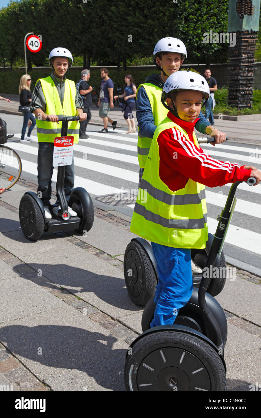 Young tourists in yellow safety vests and helmets with radio receiver on Segway sightseeing in the city of Copenhagen, Denmark Stock Photo
